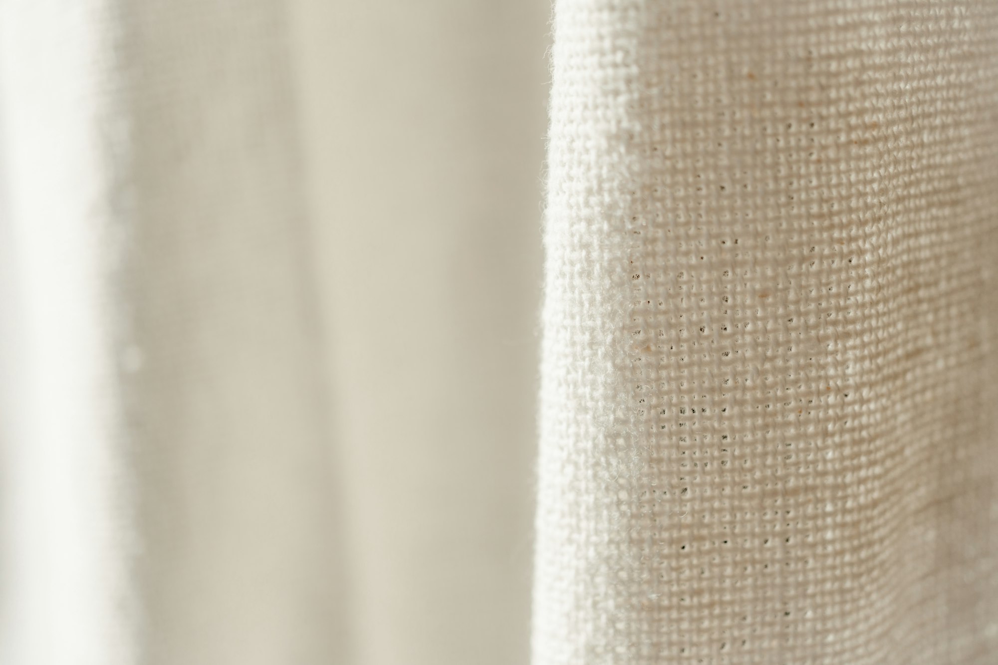 Soft linen curtain in natural light, with the loose weave catching the morning sun.
